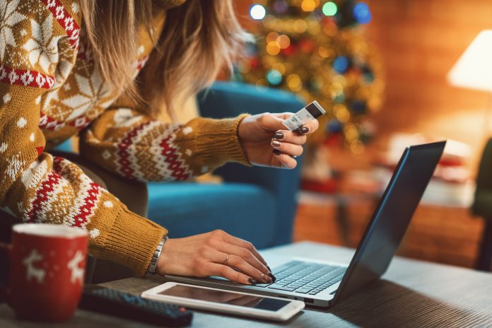 woman holiday shopping on laptop with credit card in hand
