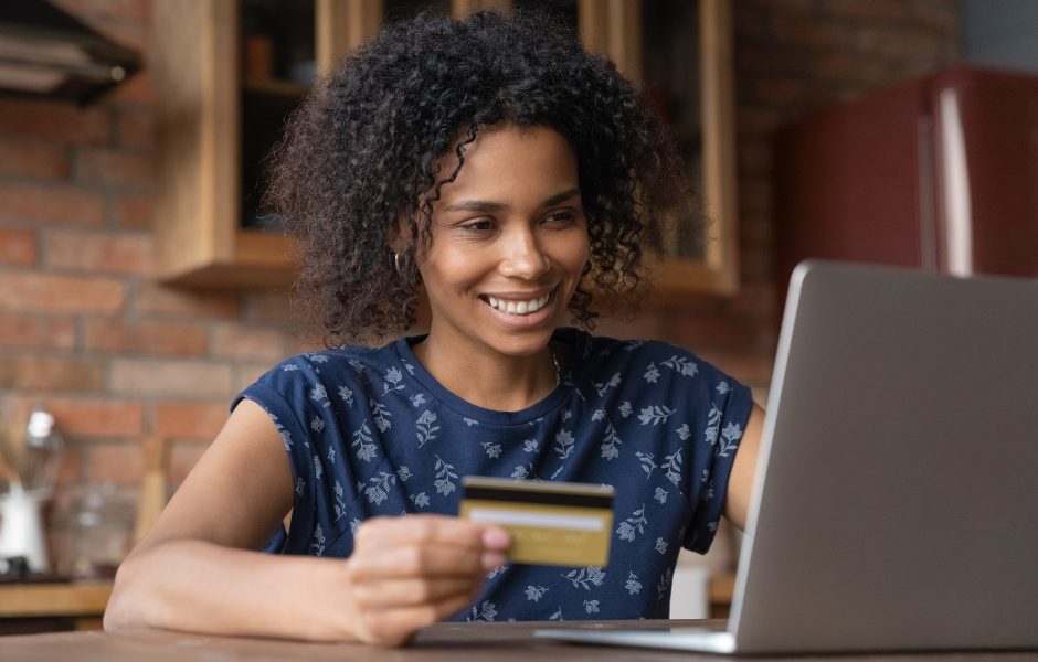 smiling woman on laptop holding credit card